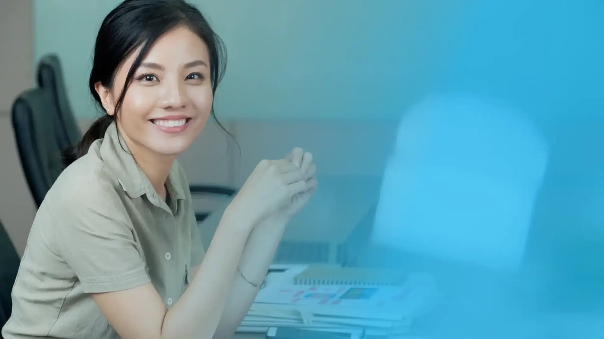 A smiling professional at a desk with documents and a laptop, symbolizing efficient workforce management for business success.